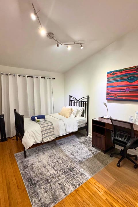 Bright bedroom with workspace, hardwood floors, and modern decor