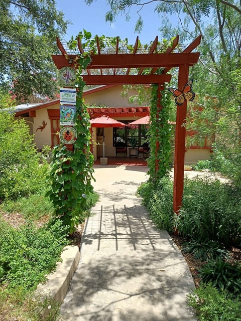Exterior front yard and front porch with arbor over sidewalk.