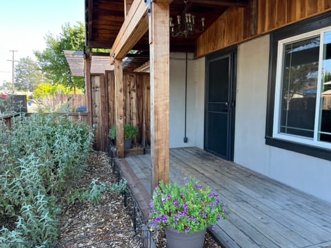 Vintage chandelier on the covered front porch. Gate leads to the graveled dog run that is also accessible through the back door in the kitchen.
