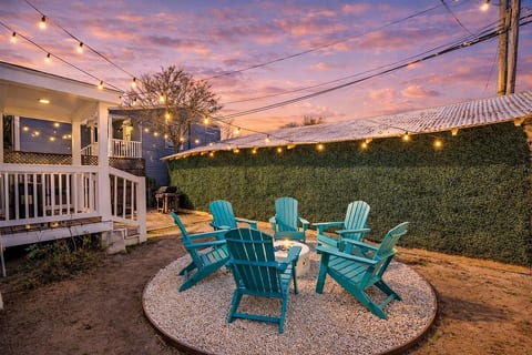 Your private 1886 oasis. This charming backyard patio features glowing string lights and Adirondack seating, perfect for evening gatherings, outdoor dining, and catching the Gulf Coast breeze at Sand and Sea Manor.