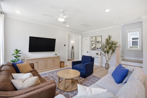 The living room is a comfortable space featuring a Hydeline leather sofa, Castlery performance fabric sofa, and World Market swivel chair to watch the Samsung 65" SmartTV from.