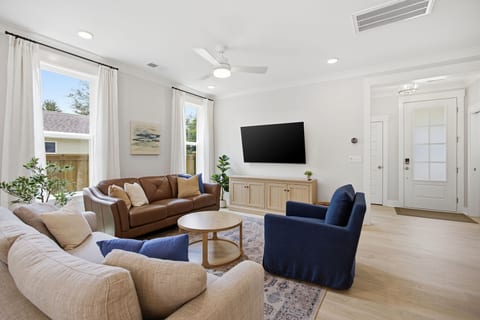 The living room is a comfortable space featuring a Hydeline leather sofa, Castlery performance fabric sofa, and World Market swivel chair to watch the Samsung 65" SmartTV from.