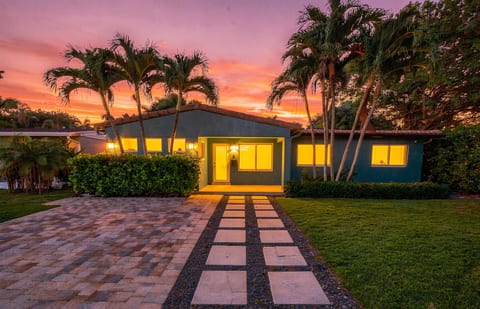 Tropical sunset curb appeal with warm lighting and palm-lined entry