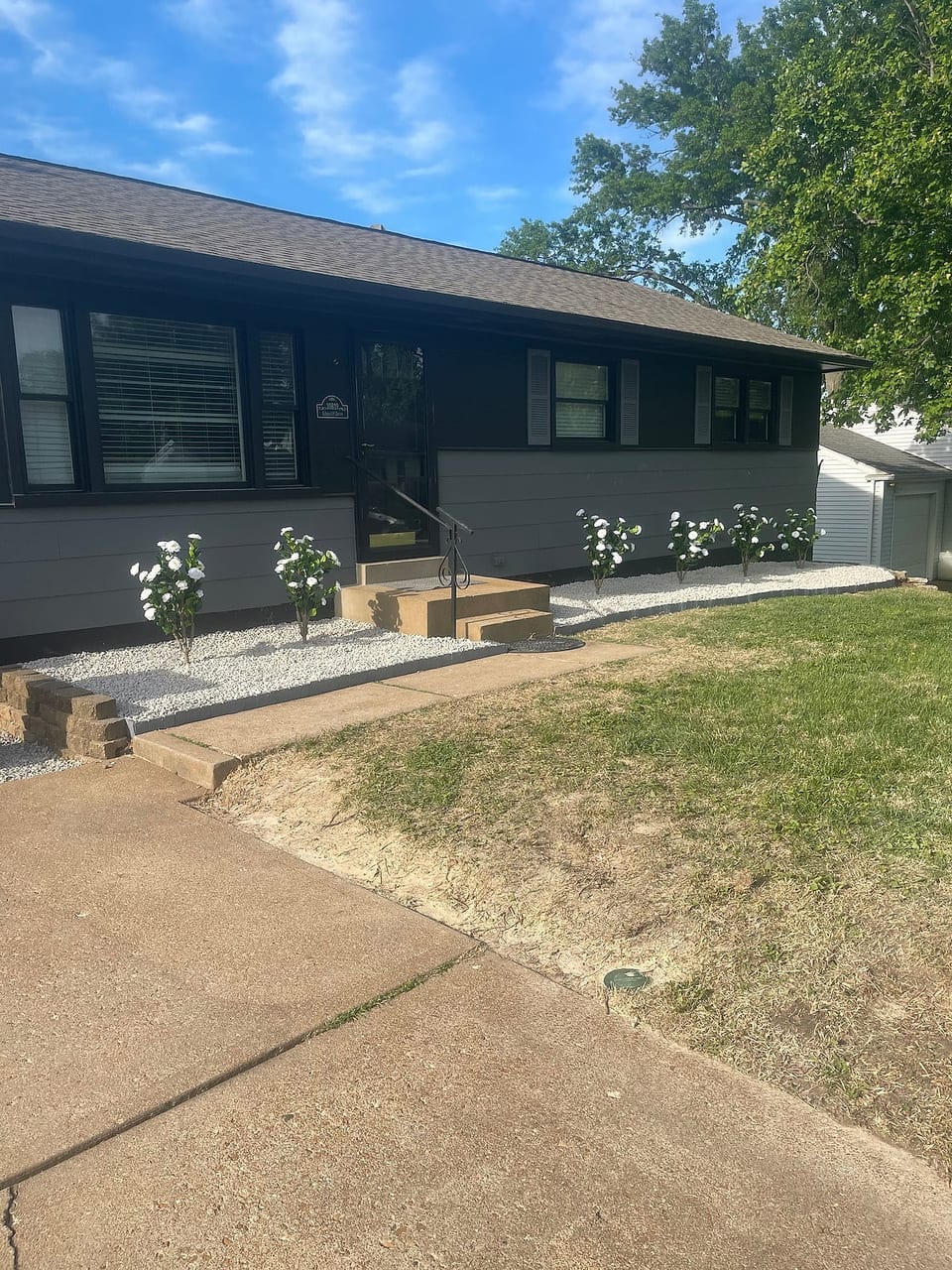 This fully remodeled home boasts a modern two-tone exterior with fresh paint, black shutters, and crisp landscaping. The front yard features a clean gravel bed with blooming white flowers and a welcoming concrete entry. A private, fenced in yard.