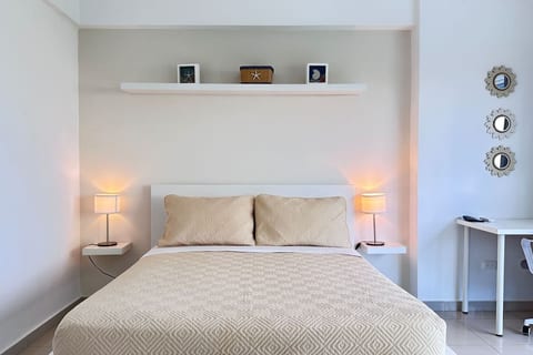 Recamara Queen para 2 personas, con almohadas cómodas y mesa de trabajo a un lado con colores neutros que acogen la habitación