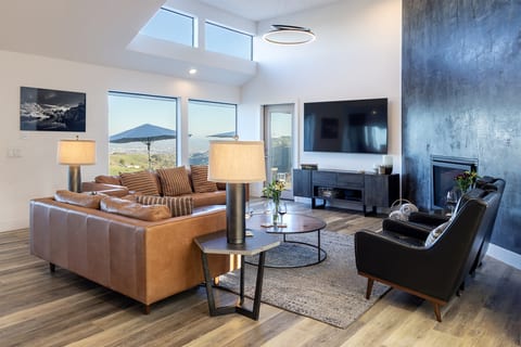 The great room opens to the valley in every direction — vineyard views to the west, a crackling fireplace to the east, and nowhere else you'd rather be in between.