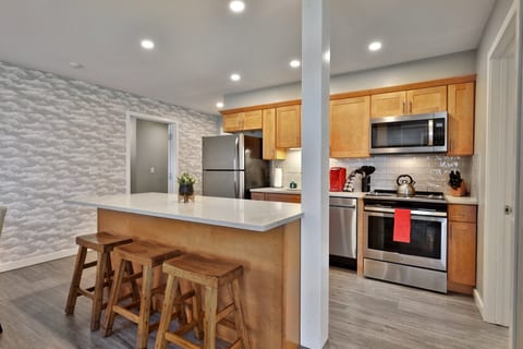 The full kitchen has an island with three stools, plus a range, microwave and refrigerator.