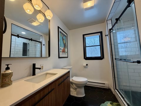 The full bathroom has a glass-enclosed shower and vanity, with no bathtub.