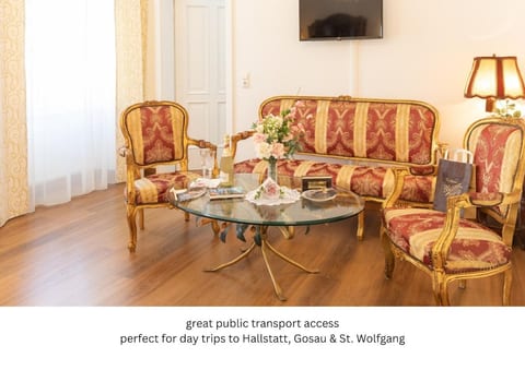 Historic elegance meets convenience. Relax in your golden seating area with TV and balcony access. Perfectly located with great public transport for iconic day trips to Hallstatt, Gosau, and St. Wolfgang. Your imperial base in the mountains!