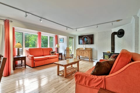 The wood stove and two sofas share the main living space; firewood is supplied.