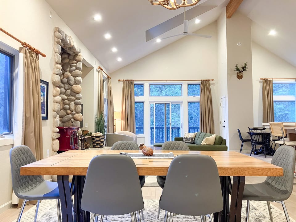 The light-filled great room with forest views and cozy seating.