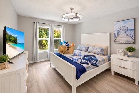 Crisp linens, a wide TV, and your beach bag already packed on the bed — this room says the only thing left to do is go