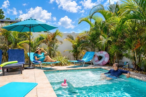 Private tropical pool oasis with loungers, shade, and lush palms