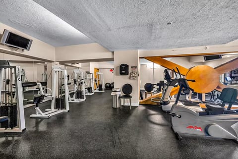 Spacious on-site gym with cardio machines, weights, and mirrored walls