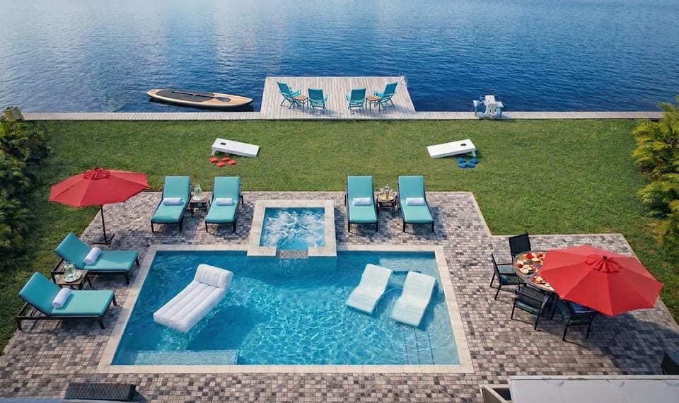 An aerial view of the outdoor oasis, with a huge patio area, hot tub, sun loungers, outdoor dining table, BBQ, decking along the canal edge and of course the pool and hot tub - what more could you want?