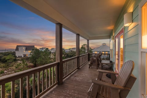 Carry your drink out to the covered deck as the sun drops behind the rooftops — porch lights on, warm air off the Gulf, and nowhere else you need to be.
