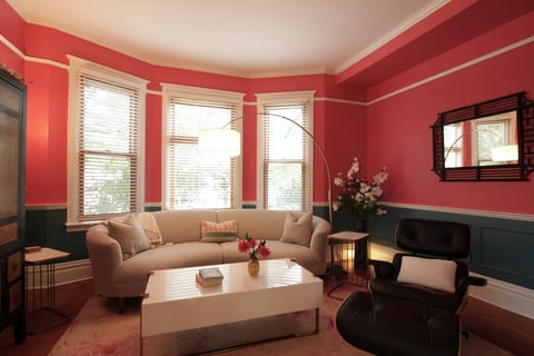 The Parlor — the home’s signature room, anchoring the turret, with a teal and coral palette, mid-century inspired furnishings, and Art Deco details.