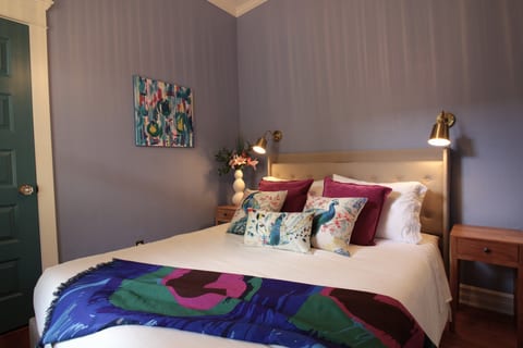 The Peacock Suite — rich blues, warm brass lighting, and peacock-inspired details create a relaxing retreat at the front of the home.