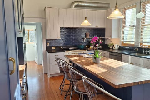 Chef’s kitchen — oversized windows, a large butcher block island, and an ILVE gas/electric range create a bright, welcoming space for cooking and shared meals.