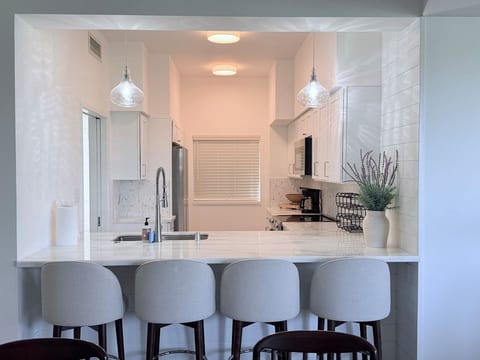 Bright, fully equipped kitchen with quartz countertops, stainless steel Frigidaire appliances, and a spacious breakfast bar with seating for four—perfect for morning coffee, casual meals, or planning your island adventures.