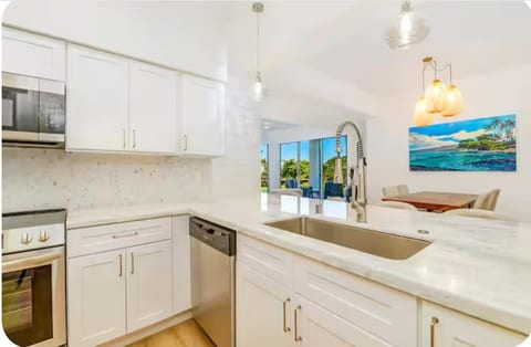 Bright, fully equipped kitchen with quartz countertops, stainless steel Frigidaire appliances, and a spacious breakfast bar with seating for four—perfect for morning coffee, casual meals, or planning your island adventures.
