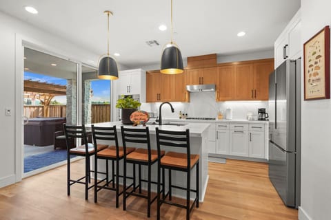 Bright, fully equipped kitchen featuring stainless steel appliances, a spacious island with seating for four, and a drip coffee maker. Plenty of counter space makes it easy to prepare meals and gather together.