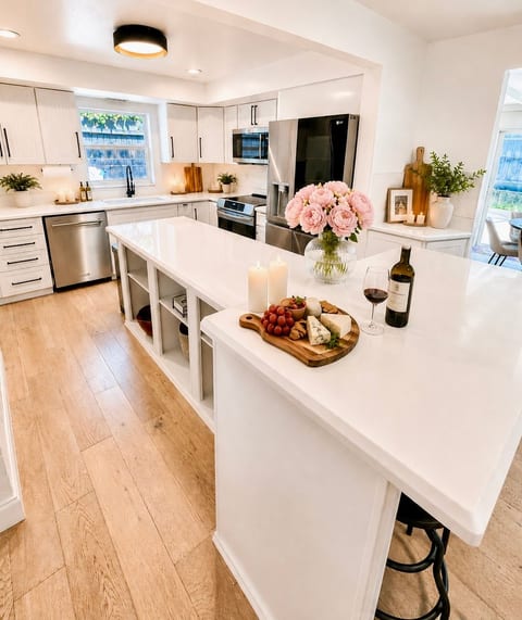 Fully stocked kitchen with induction cooktop, convection oven, and LG refrigerator with craft ice maker. Note: flowers, candles, and food shown are photo styling only and not provided.