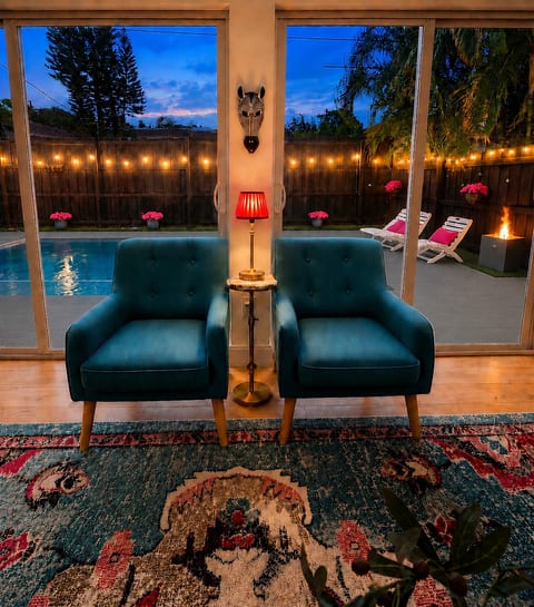 Pool glowing, fire pit burning, string lights strung across a South Florida sky at dusk. Pull up a chair.