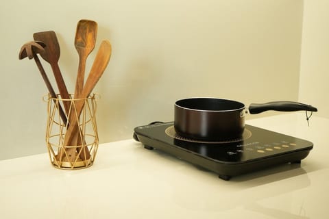 Induction cooktop, sink, and essential cookware provided.