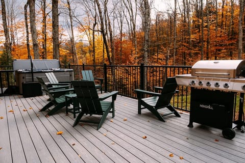 Deck with a premium hot tub, adirondack seating, grill and views of the VT woods.