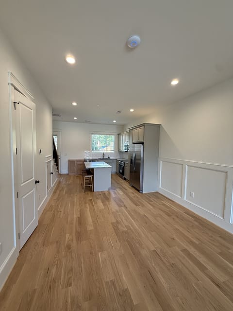 Bright open-concept space with modern kitchen, wood floors, and natural light