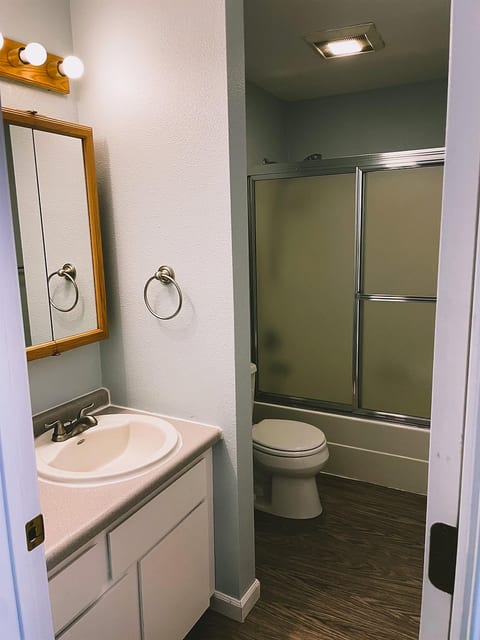 Bright bathroom with vanity, tub-shower combo, and modern wood-look floors