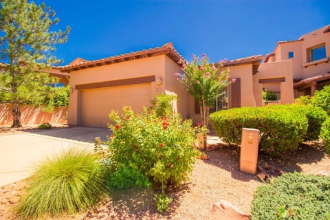 Single-level home with Southwestern architecture, beautifully landscaped grounds, vibrant flowers, and a private two-car garage.
