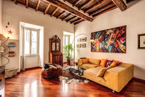 living room with parquet floors and original wooden beams of the 1500 with a super comfortable sofa, TV, antique furniture in fusion with modern style