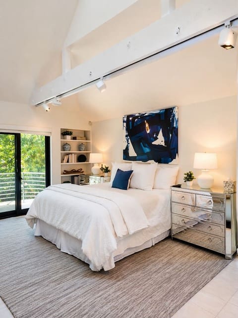 Spacious king bedroom with vaulted ceilings, a Smart TV, and sliding doors that bring in plenty of natural light. A comfortable and relaxing retreat with views of the surrounding greenery.