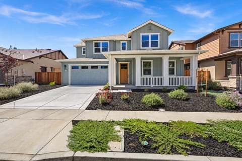 A welcoming exterior view of this newly built Napa home with a covered front porch, attractive landscaping, and an attached two-car garage. The bright, beautifully maintained entrance creates a warm welcome.