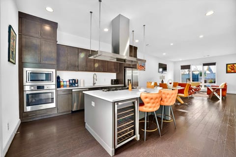 Modern open kitchen with island seating, wine fridge, and bright dining space