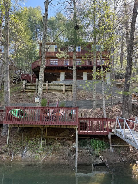 View of Watauga Lake Hideaway from the lakefront. The property is built into a steep wooded hillside, with stairs connecting the lake and dock area to the condos above.