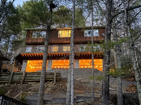 Watauga Lake Hideaway glowing at dusk. Nestled among the trees, the lighted covered common area creates a warm, inviting place to relax after a day on the lake.