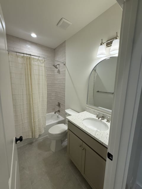 Bright full bathroom with granite vanity and tub-shower combo