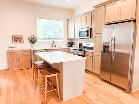 Bright modern kitchen with waterfall island and stainless appliances