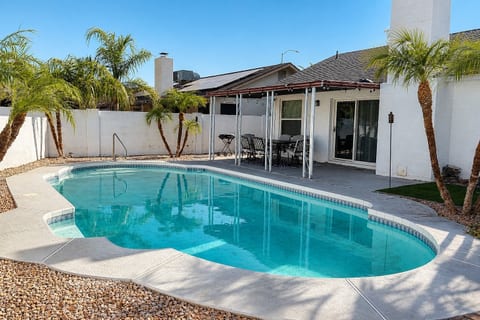 Sunny private pool oasis with covered patio, palms, and outdoor seating