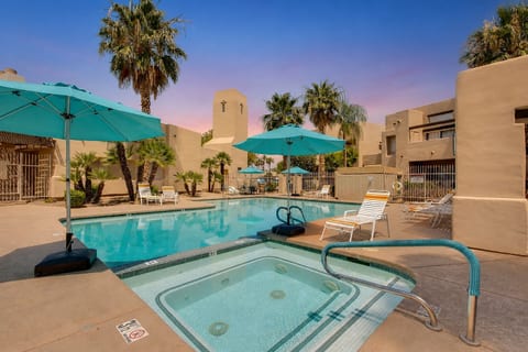 Resort-style pool and hot tub with palm trees and shaded loungers
