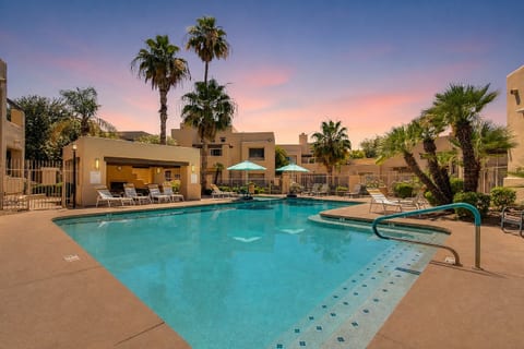 Resort-style pool and spa oasis with palm trees at sunset