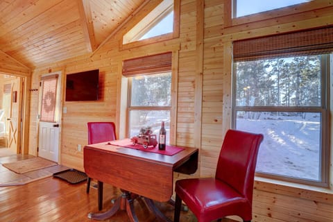 Dine by the window in this charming nook featuring rich wood walls, cathedral-style windows, and red leather chairs that bring a pop of color and warmth to your meals.
