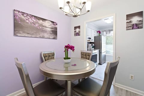 The modern, round glass table and comfortable chairs offer a stylish setting for your stay. You will find beautiful art, a chandelier, and a view into the kitchen, creating a bright and inviting space.
