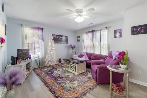 Discover your cozy retreat, designed for relaxation. Unwind on the plush purple sofa, bathed in natural light. Your perfect escape for a peaceful, comfortable stay awaits.