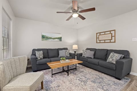 Bright living room with comfortable seating, ceiling fan, and cozy décor, perfect for relaxing.