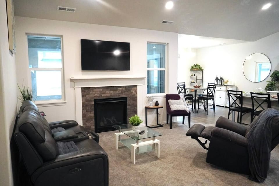 Cozy open living room with fireplace, recliners, TV, and dining area