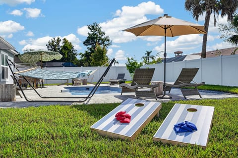 Private pool oasis with hammock, loungers, and backyard games